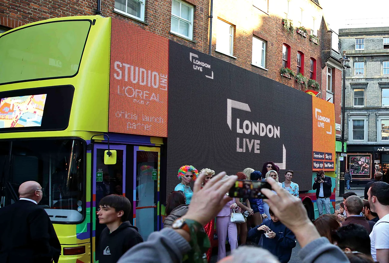 Crowd photographing a branded bus at a launch event